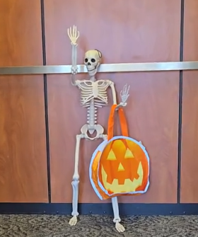 plastic skeleton holding a trick or treat bag